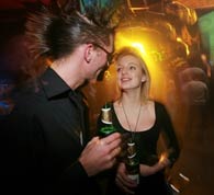 Ragazzo con capelli pettinatura Punk e ragazza bionda bevono birra sabmiller in discoteca sotto luci laser psichedeliche